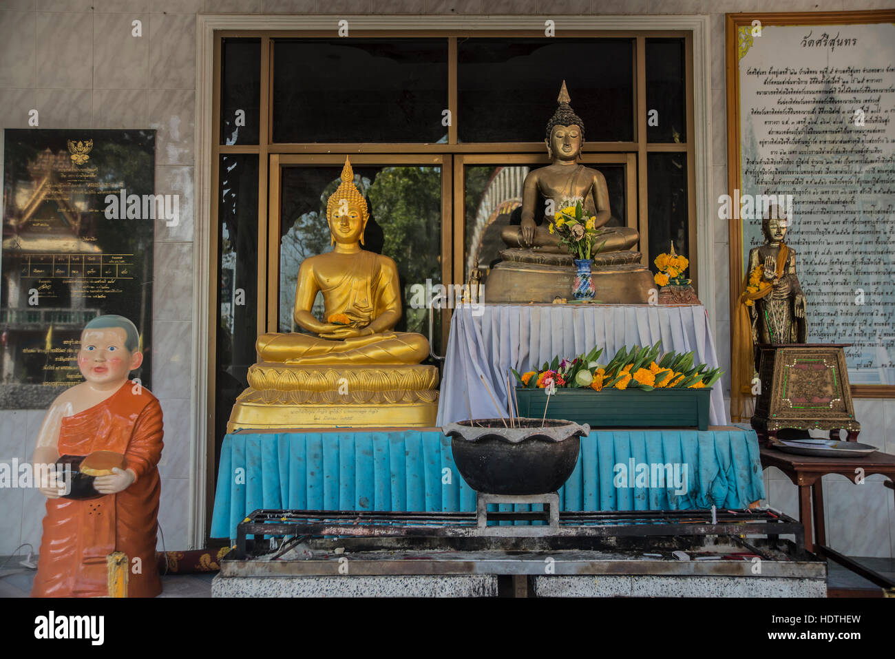 Many flowers in front of budha. gold monk statue decorated with flower and ivory. Gold Buddha with flower Stock Photo