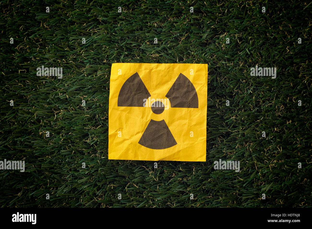 Radiation warning sign on a green grass. Close up Stock Photo - Alamy
