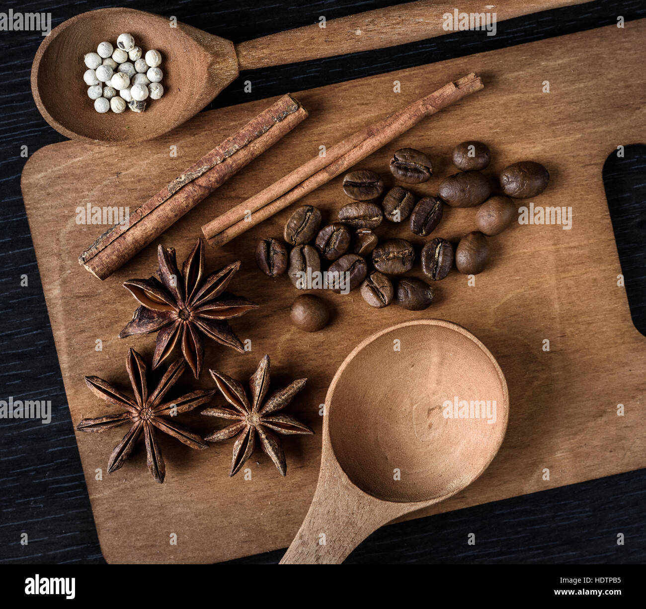 coffee, star anise, cinnamon, spoon on a wooden cutting Board on dark background Board Stock Photo