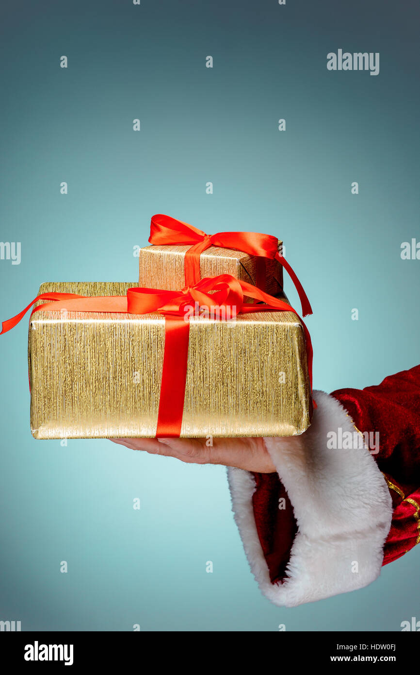 The hand of santa claus holding a gift on blue background Stock Photo ...