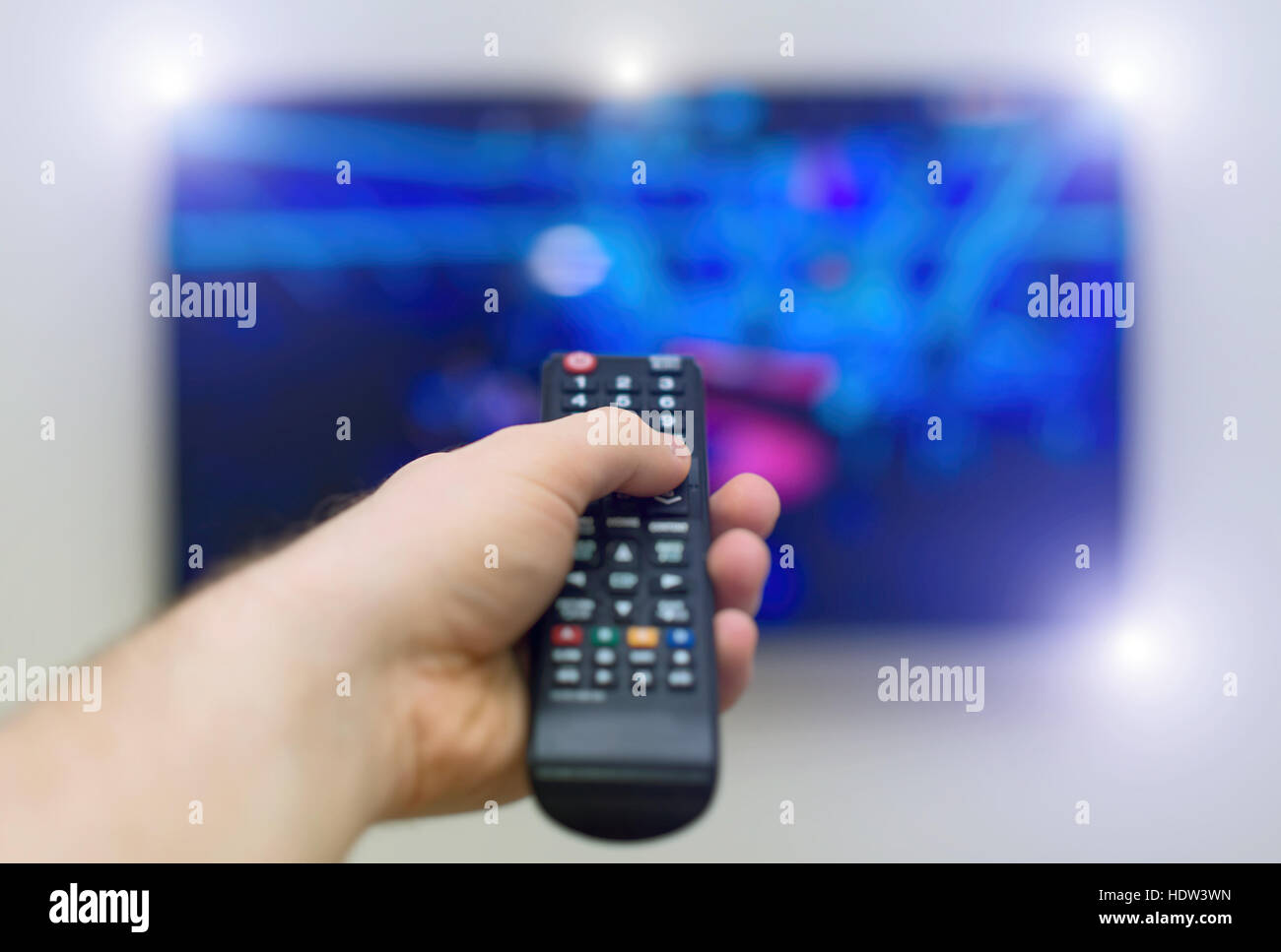 Male hand holding TV remote control. Stock Photo