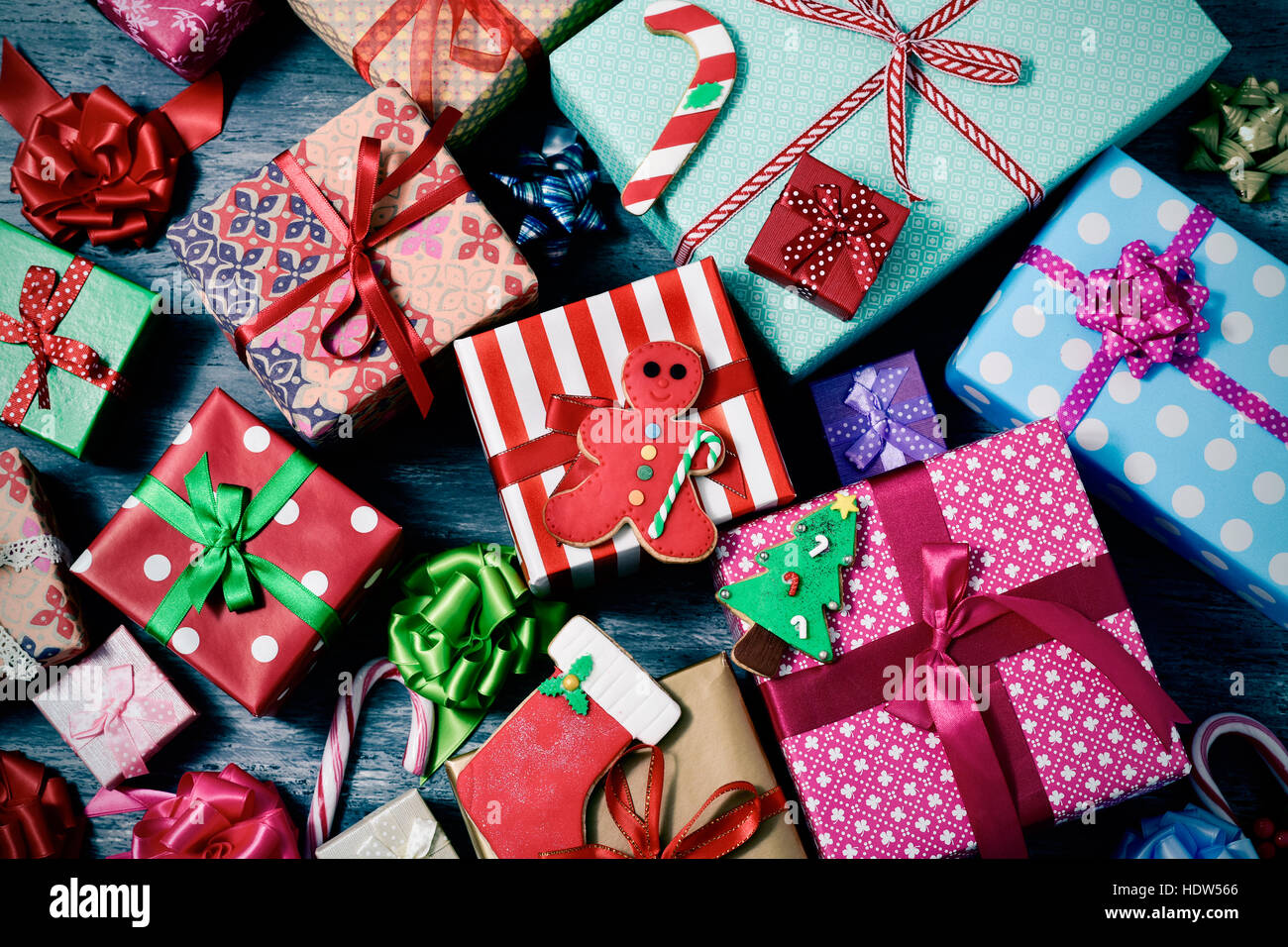 high-angle shot of some christmas cookies and a pile of gifts wrapped in nice papers and tied with ribbons of different colors on a rustic wooden surf Stock Photo