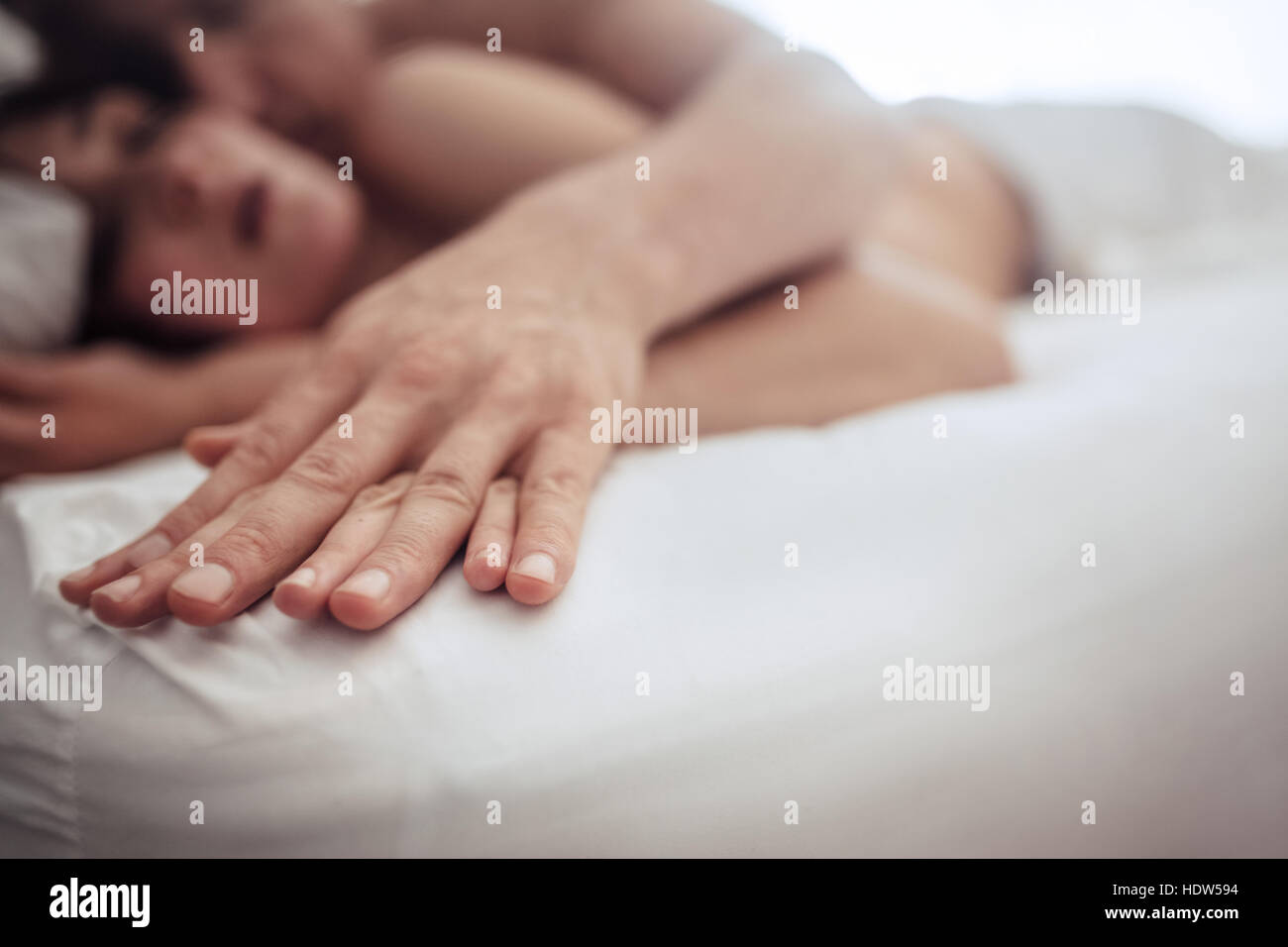 Sensual couple in bed having intimate sex. Focus on hands man and woman. Stock Photo