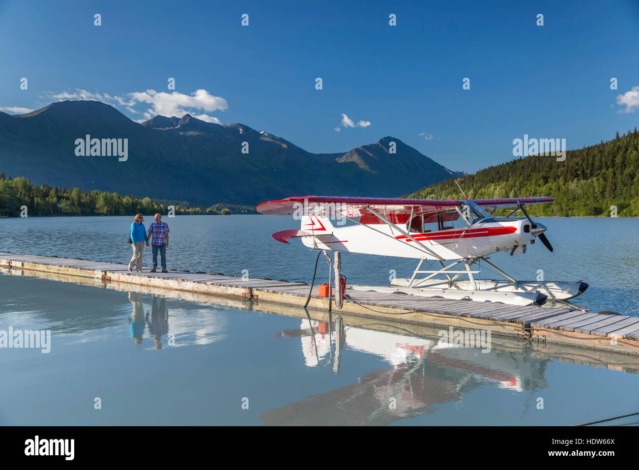 A woman and a man stand on a dock where a float plane is docked, Trail Lake Float Plane Base, Moose Pass, Kenai Peninsula, Southcentral Alaska, USA Stock Photo