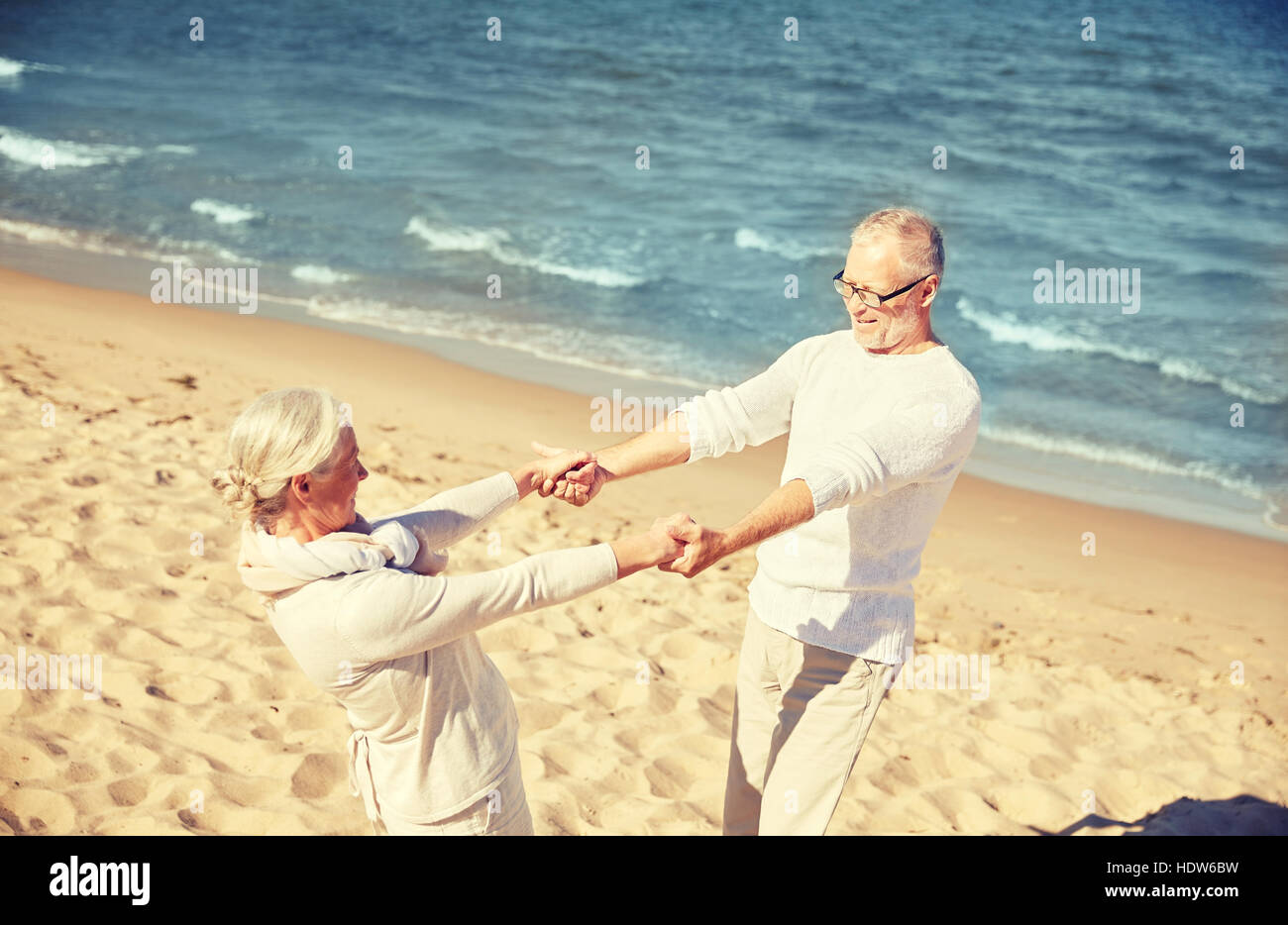 Elderly couple holding hands on beach hi-res stock photography and ...