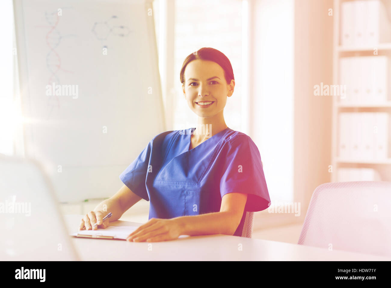 happy female doctor or nurse writing to clipboard Stock Photo - Alamy
