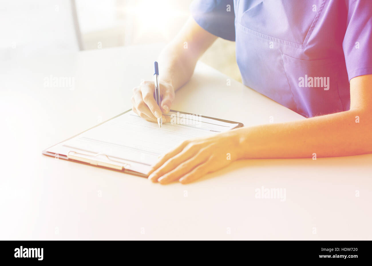 close up of doctor or nurse writing to clipboard Stock Photo - Alamy