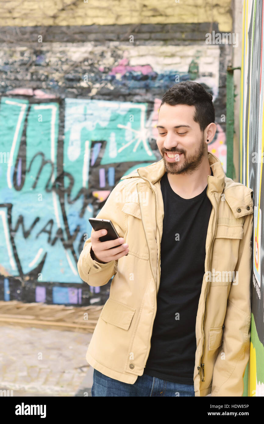 Casual young latin man using a smartphone. Urban scene Stock Photo