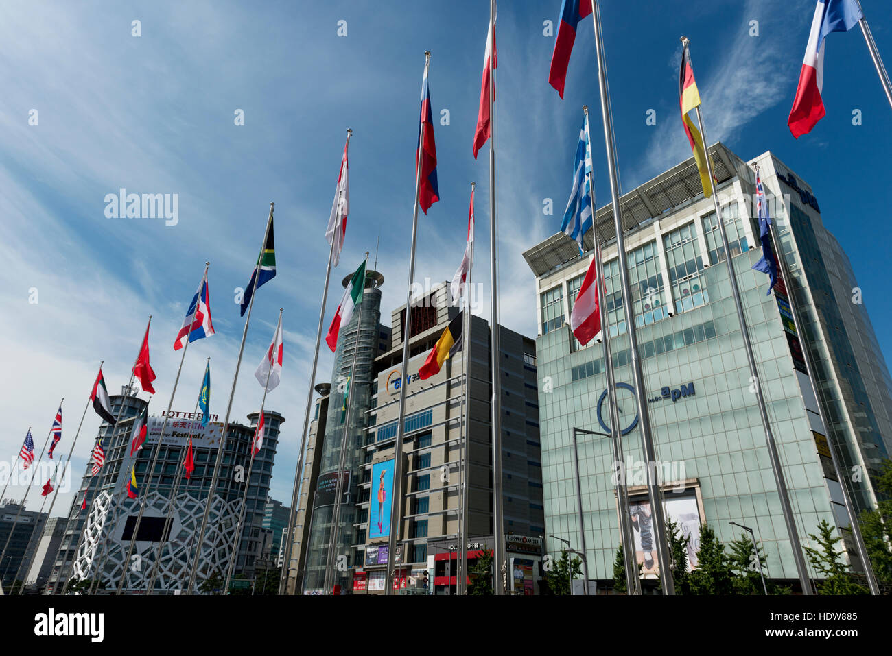 Modern buildings with digital screens for advertising and international flags on poles in a row; Seoul, South Korea Stock Photo
