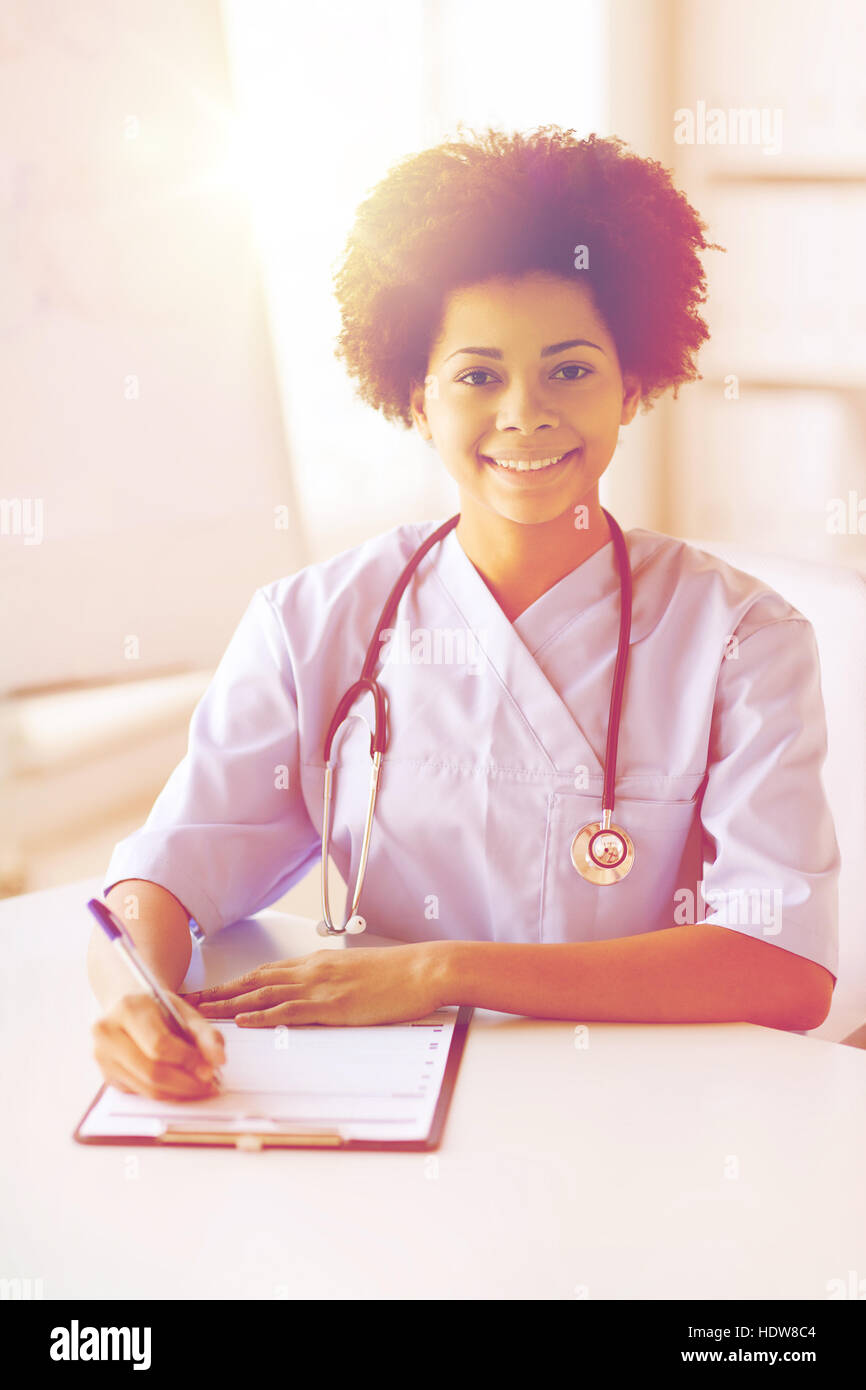 happy female doctor or nurse writing to clipboard Stock Photo - Alamy