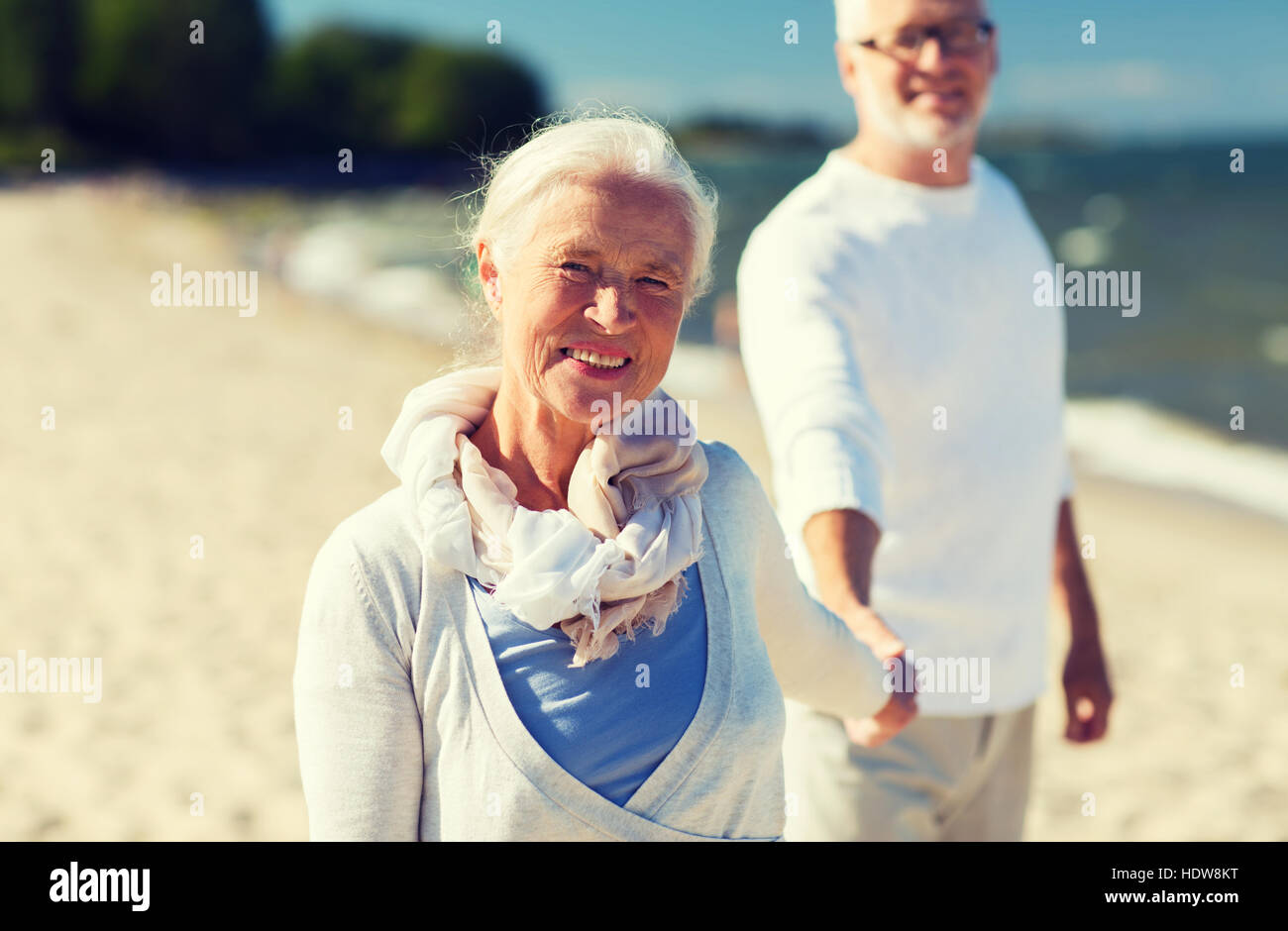 happy senior couple holding hands on summer beach Stock Photo - Alamy