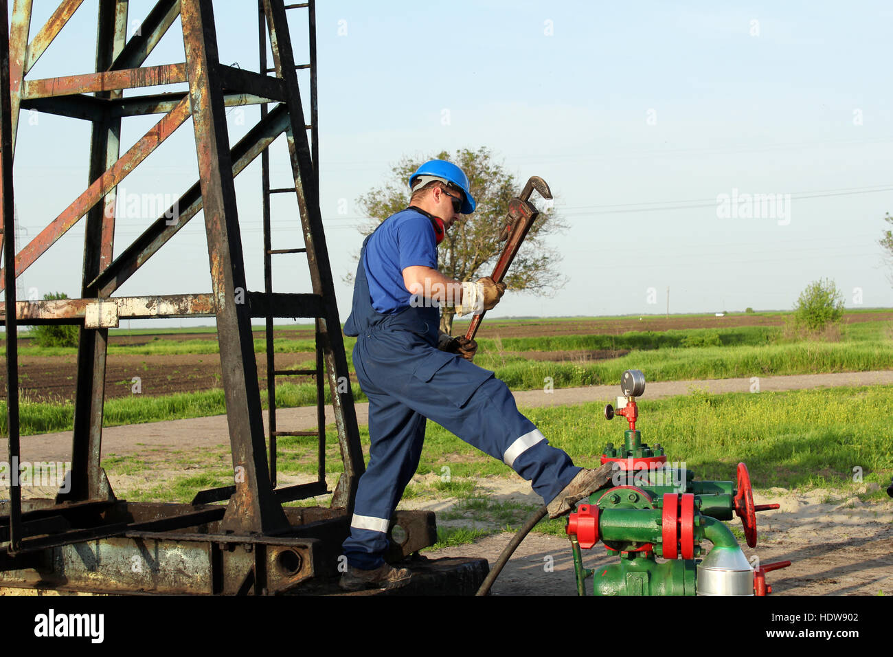 worker with pipe wrench on oilfield pipeline Stock Photo