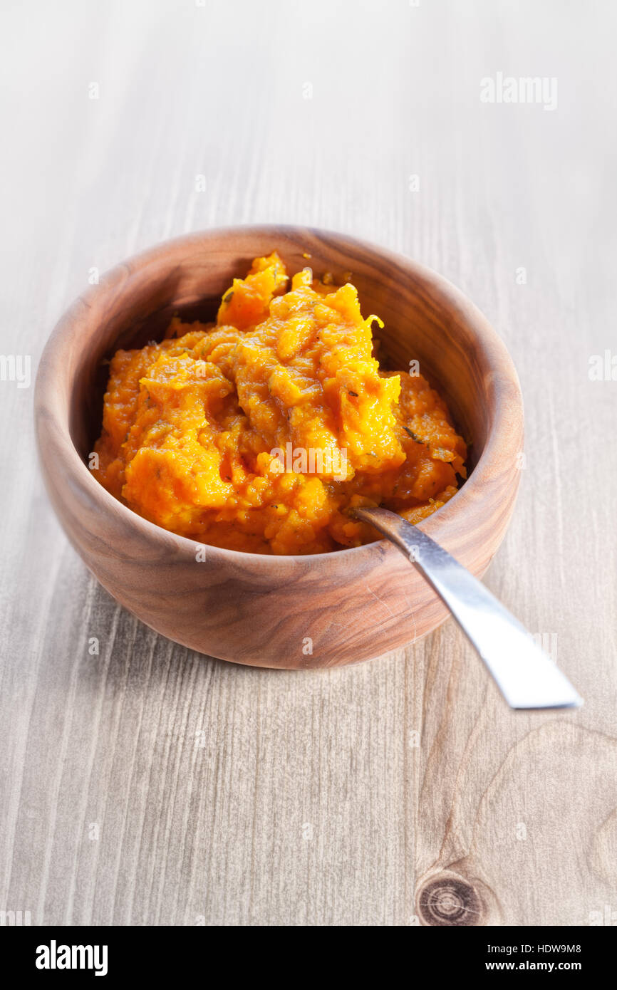 Pumpkin puree with a spoon on a wooden surface Stock Photo