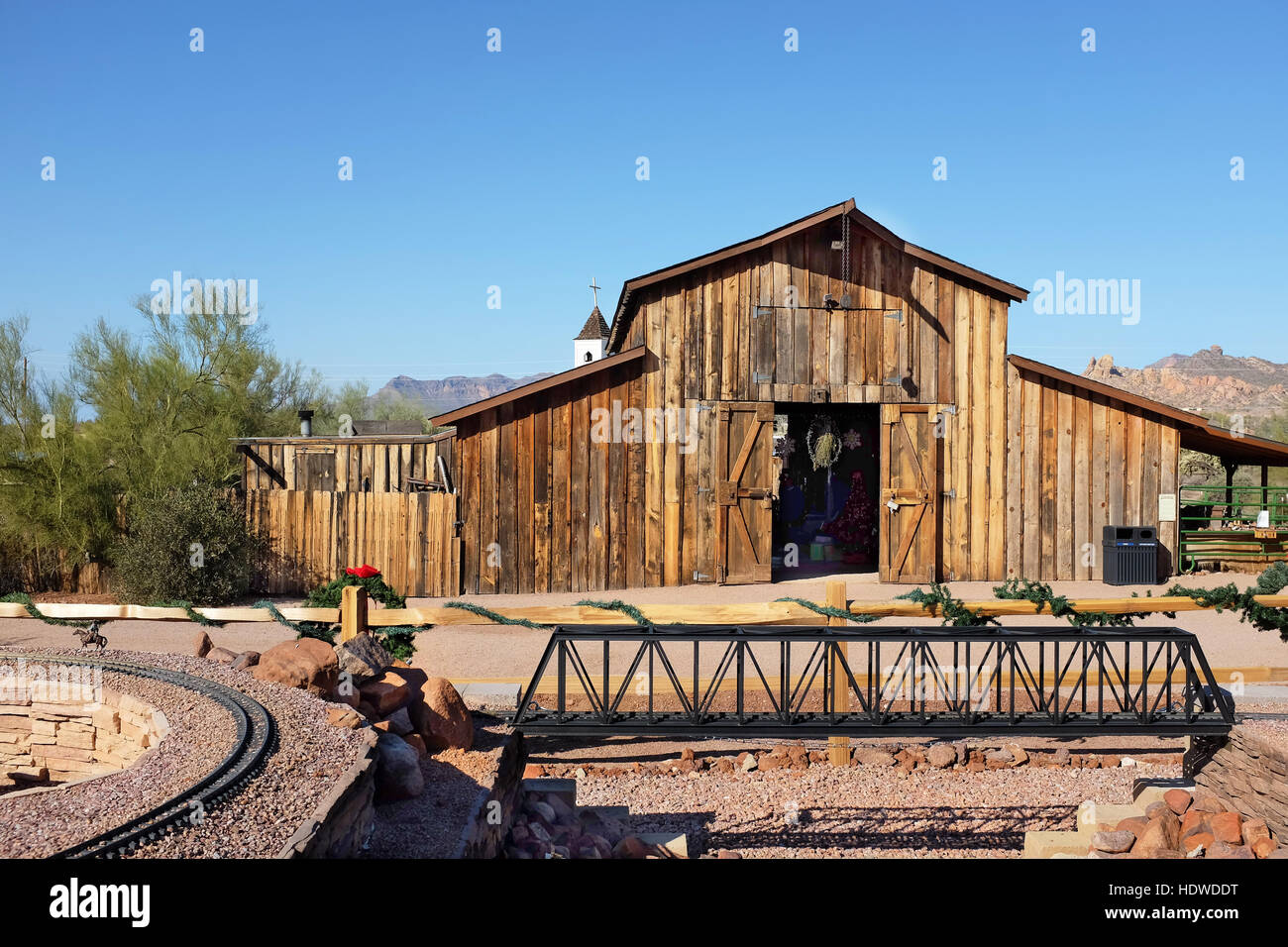 Apacheland Barn and Model Railroad trestle with the Elvis Memorial Chapel in the background at the Superstition Mountain Museum in Apache Junction, Ar Stock Photo