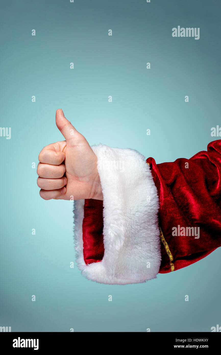 Santa Claus hand showing thumbs up on blue background Stock Photo - Alamy
