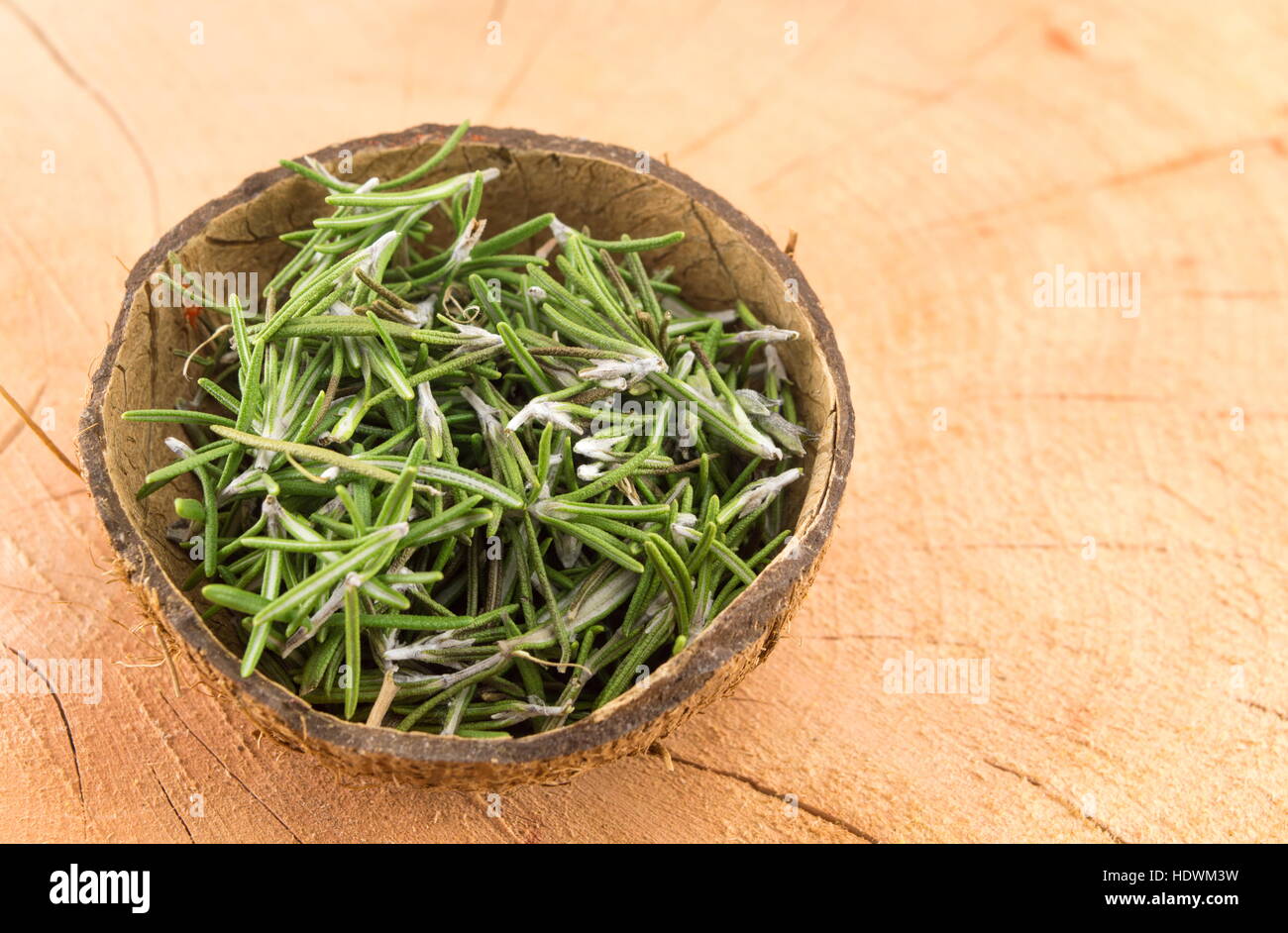 rosemary in a coconut shell on a wooden table Stock Photo