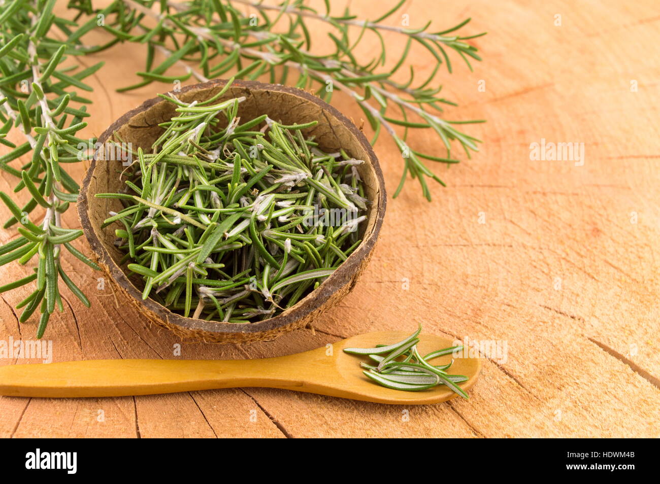 rosemary in a coconut shell with a wooden spoon Stock Photo