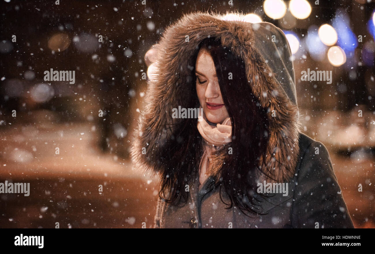 Woman under falling snow at night Stock Photo