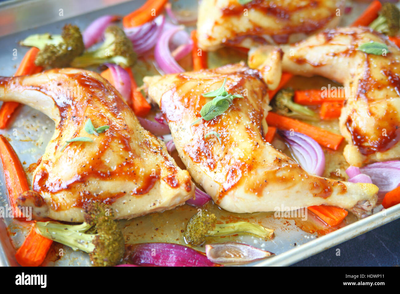 Chicken quarters roasted with carrots, onions and broccoli on sheet pan