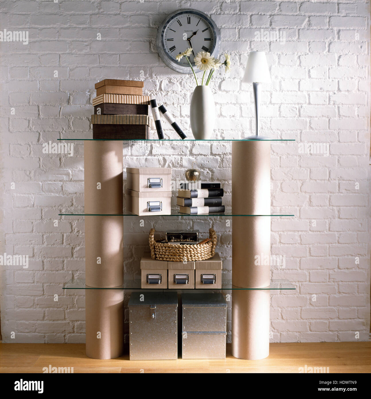 Simple glass and cylinder shelving with small storage boxes Stock Photo