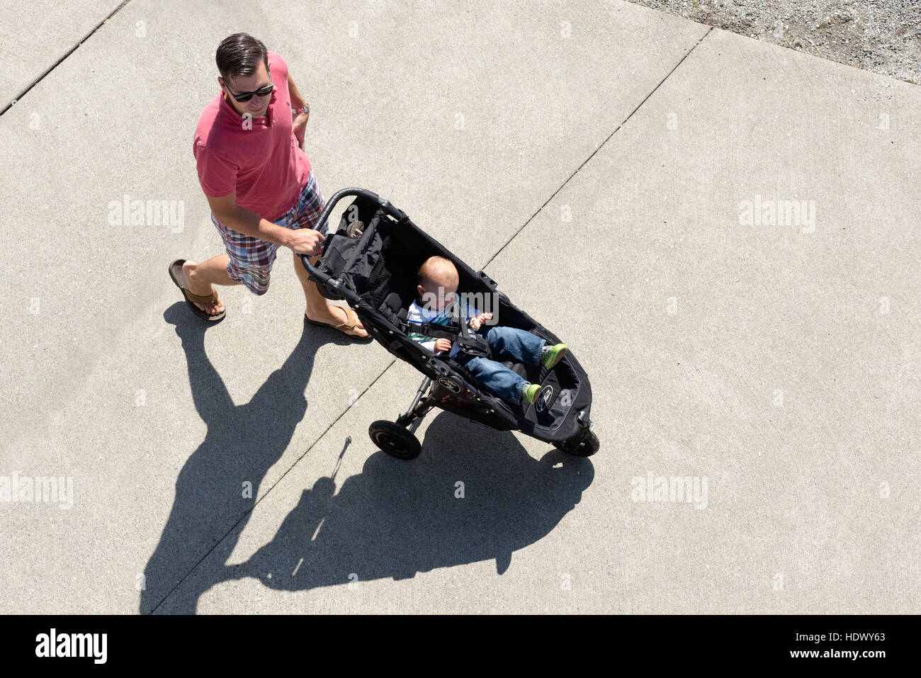 Father pushing toddler in a stroller in Port Plaza, Olympia, Washington. Stock Photo