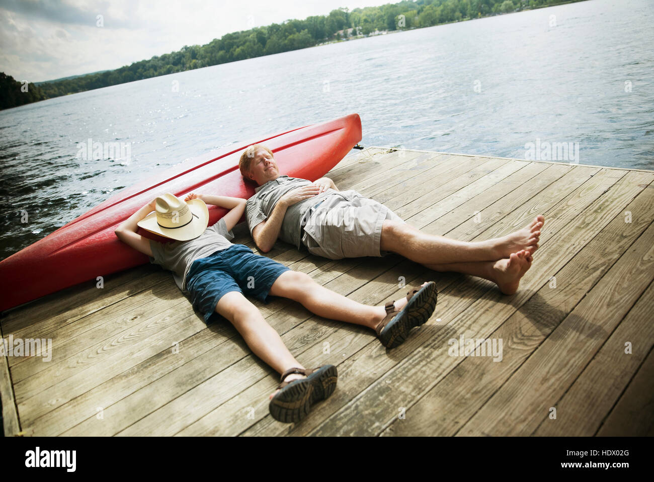 Caucasian father and son laying on wooden dock Stock Photo