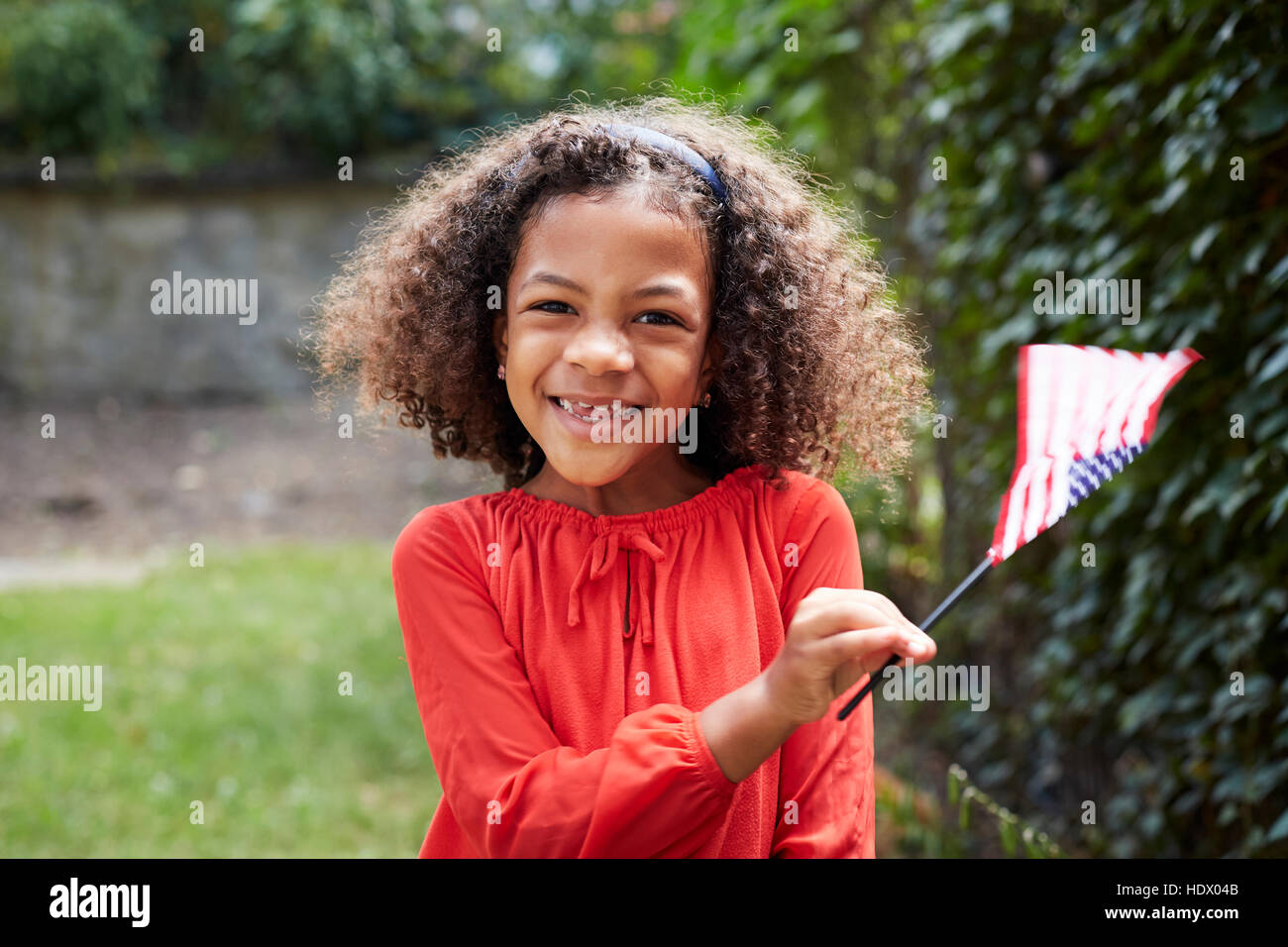 Portrait of smiling Mixed Race girl waving little American flag Stock Photo