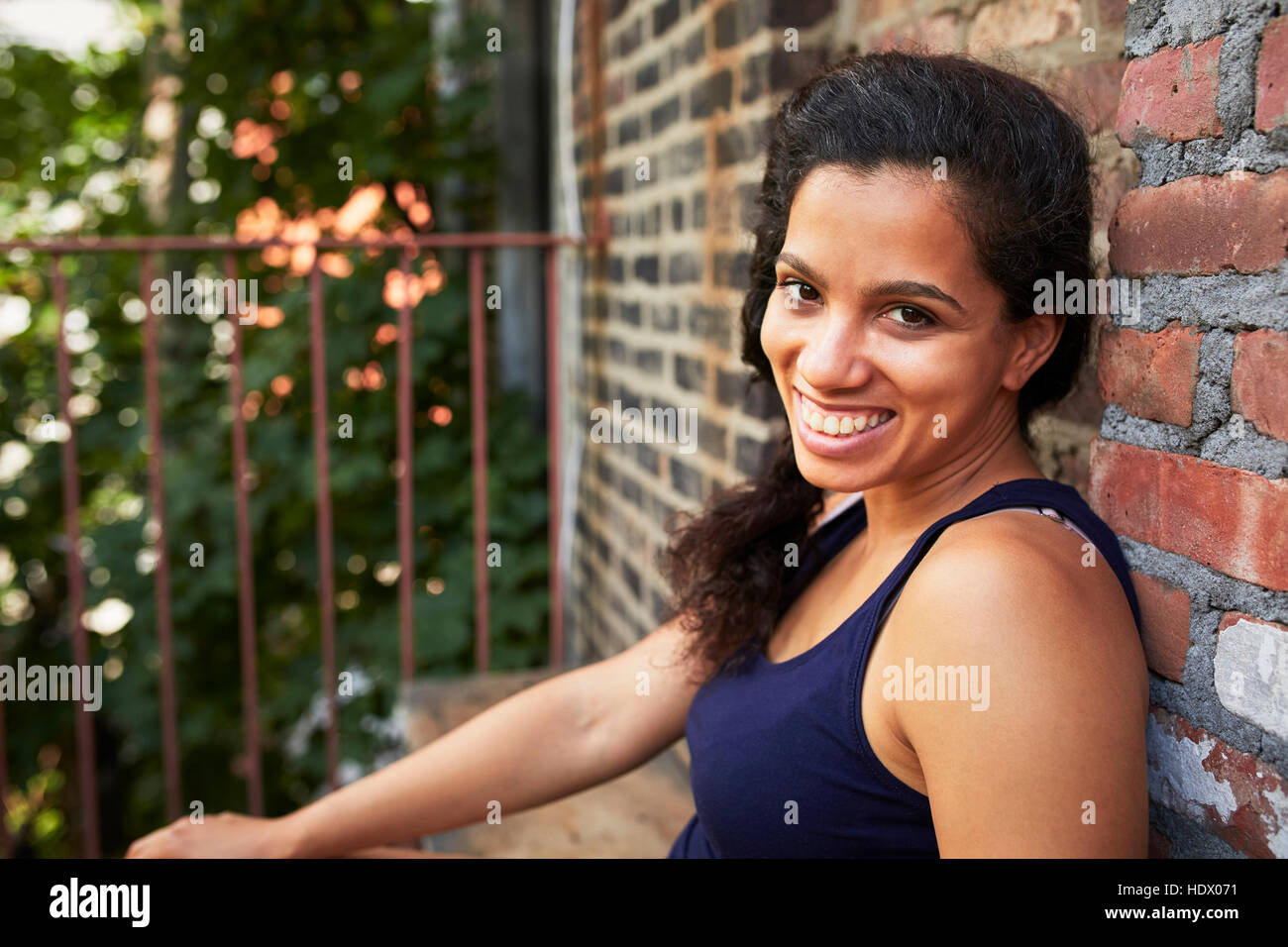 Portrait of smiling woman sitting on urban fire escape Stock Photo