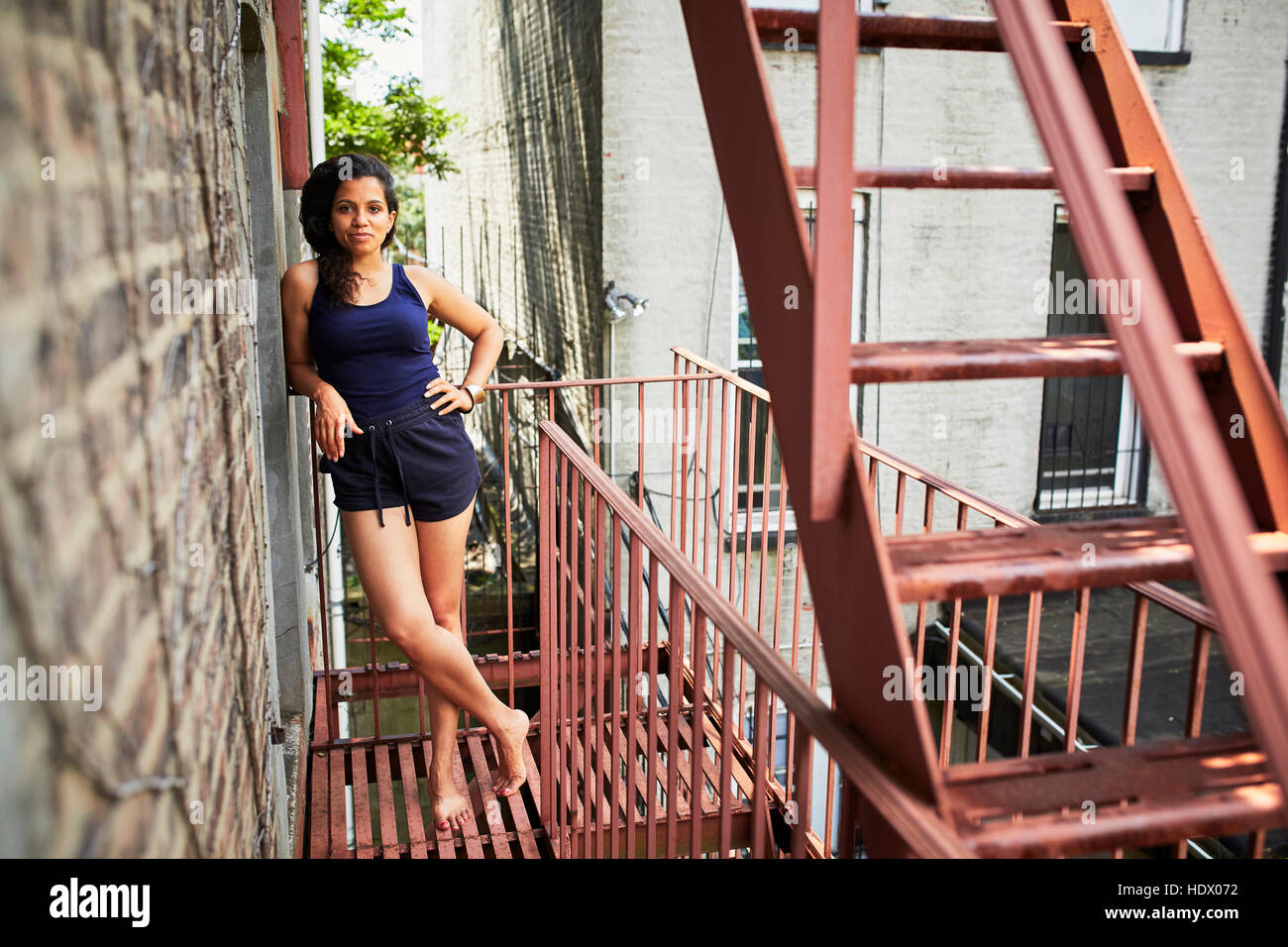Portrait of smiling woman standing on urban fire escape Stock Photo