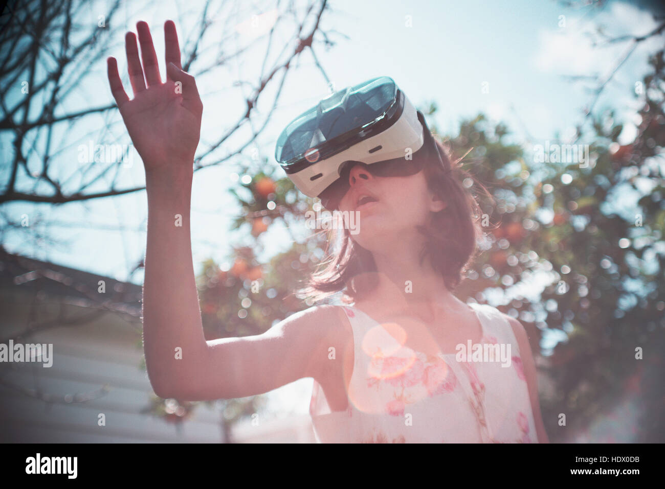 Mixed Race girl using virtual reality goggles outdoors Stock Photo