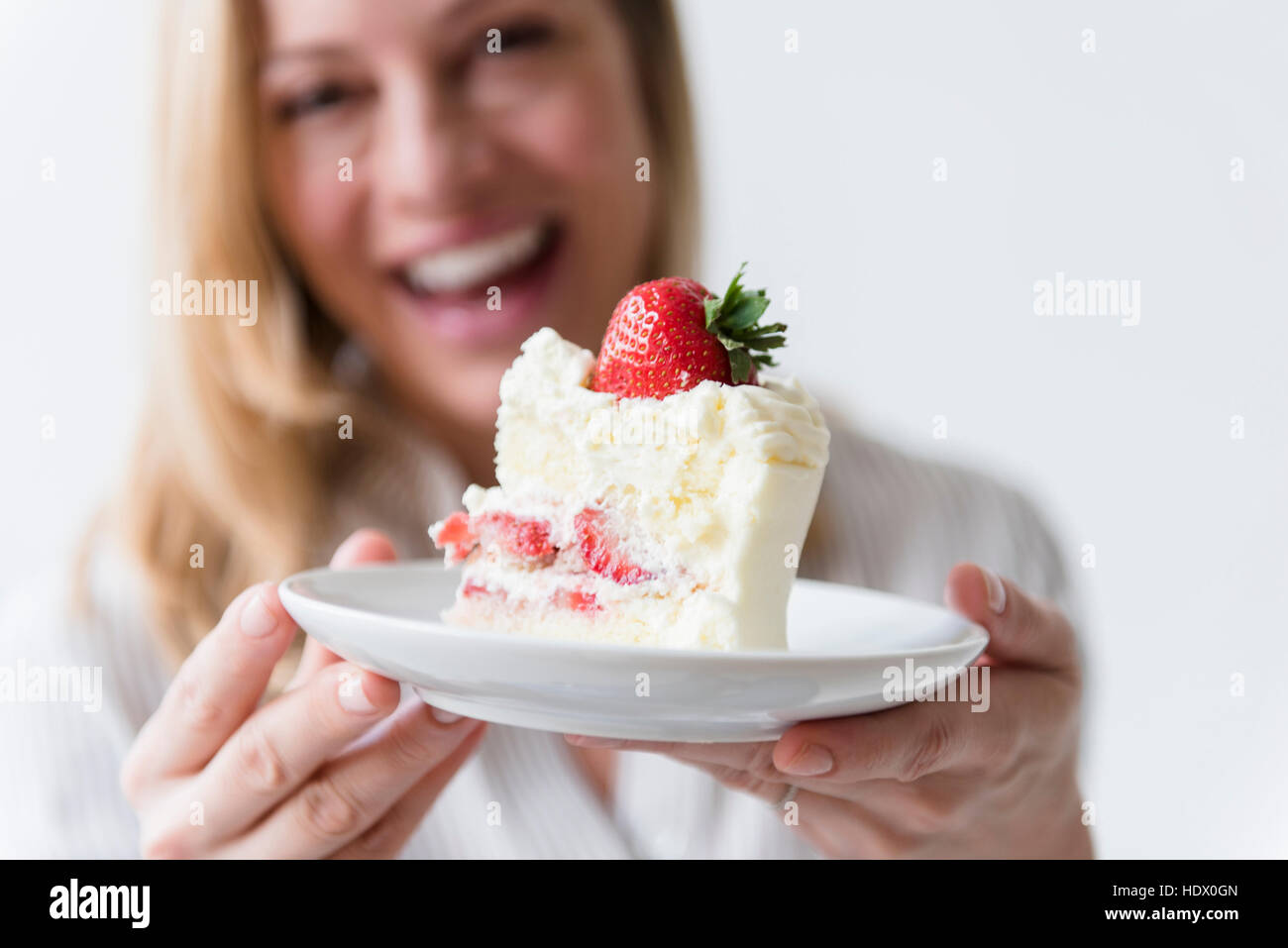 Caucasian woman holding slice on vanilla cake with strawberry Stock Photo