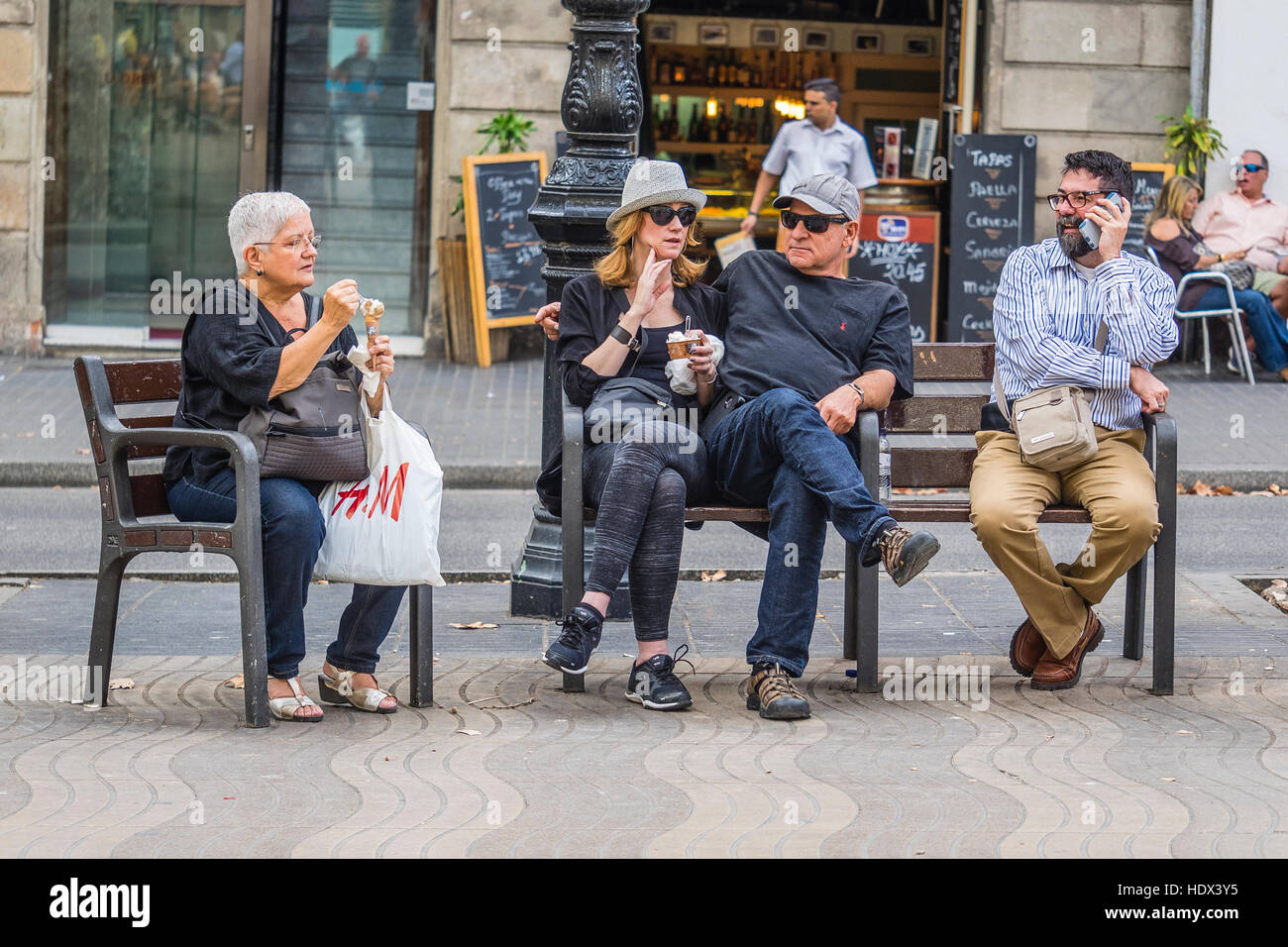 A group of four people sitting in public seating on Las Ramblas in Barcelona, Spain. Stock Photo