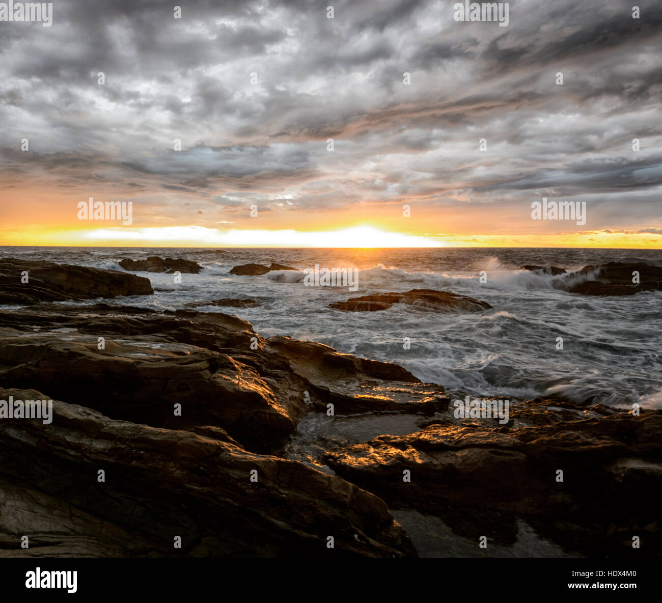 Dramatic atmospheric sunset over large waves on the beach at Bermagui