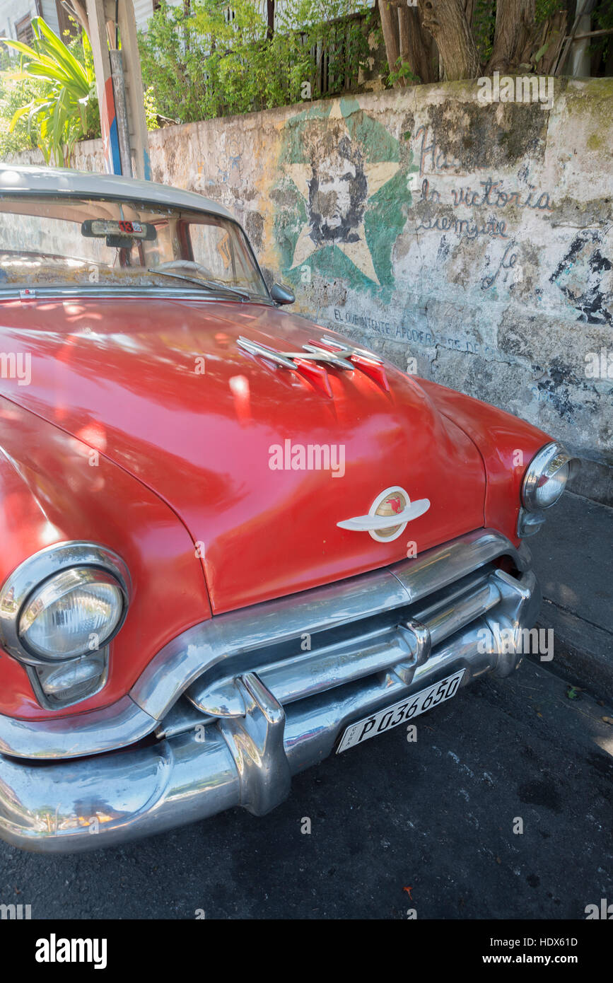 Cuban classic American car with revolutionary graffiti on wall Stock Photo