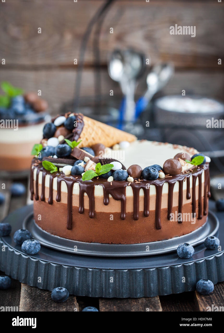 Delicious three chocolate mousse cake decorated with waffle cone, fresh blueberry, mint, candies