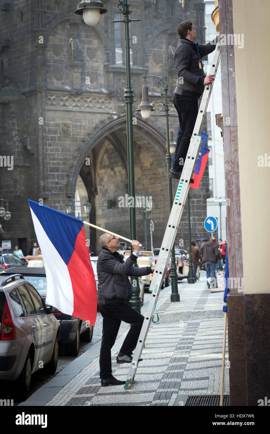 Two men prepare to put up a Czech flag on a street near the mediaeval Powder Tower in Prague Stock Photo