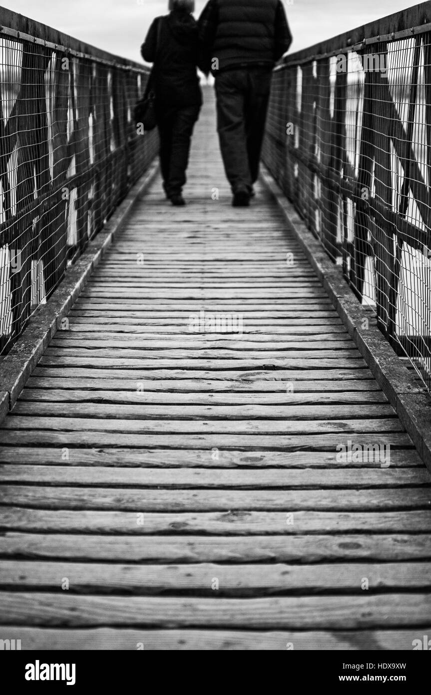 No destination as such, but the couple continue their slow saunter across the walkway regardless. Stock Photo