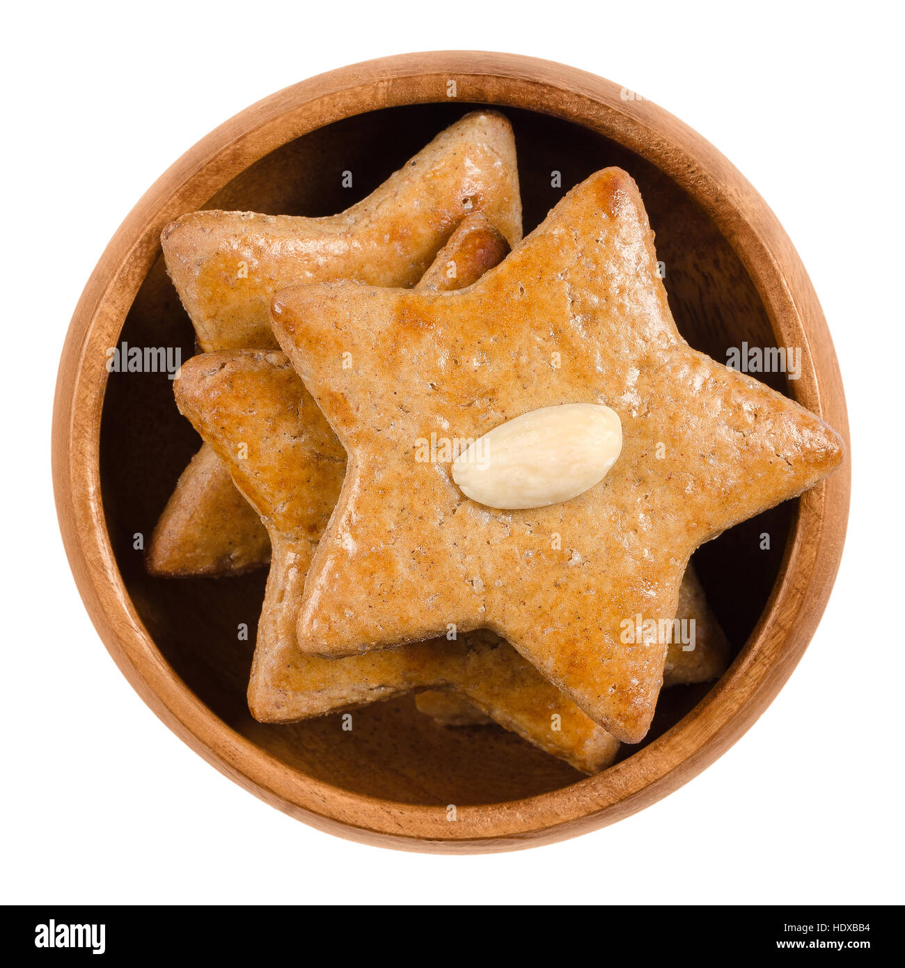 Gingerbread stars in wooden bowl. Sweet baked goods. Brown, flat and star-shaped with an almond half on top. Stock Photo