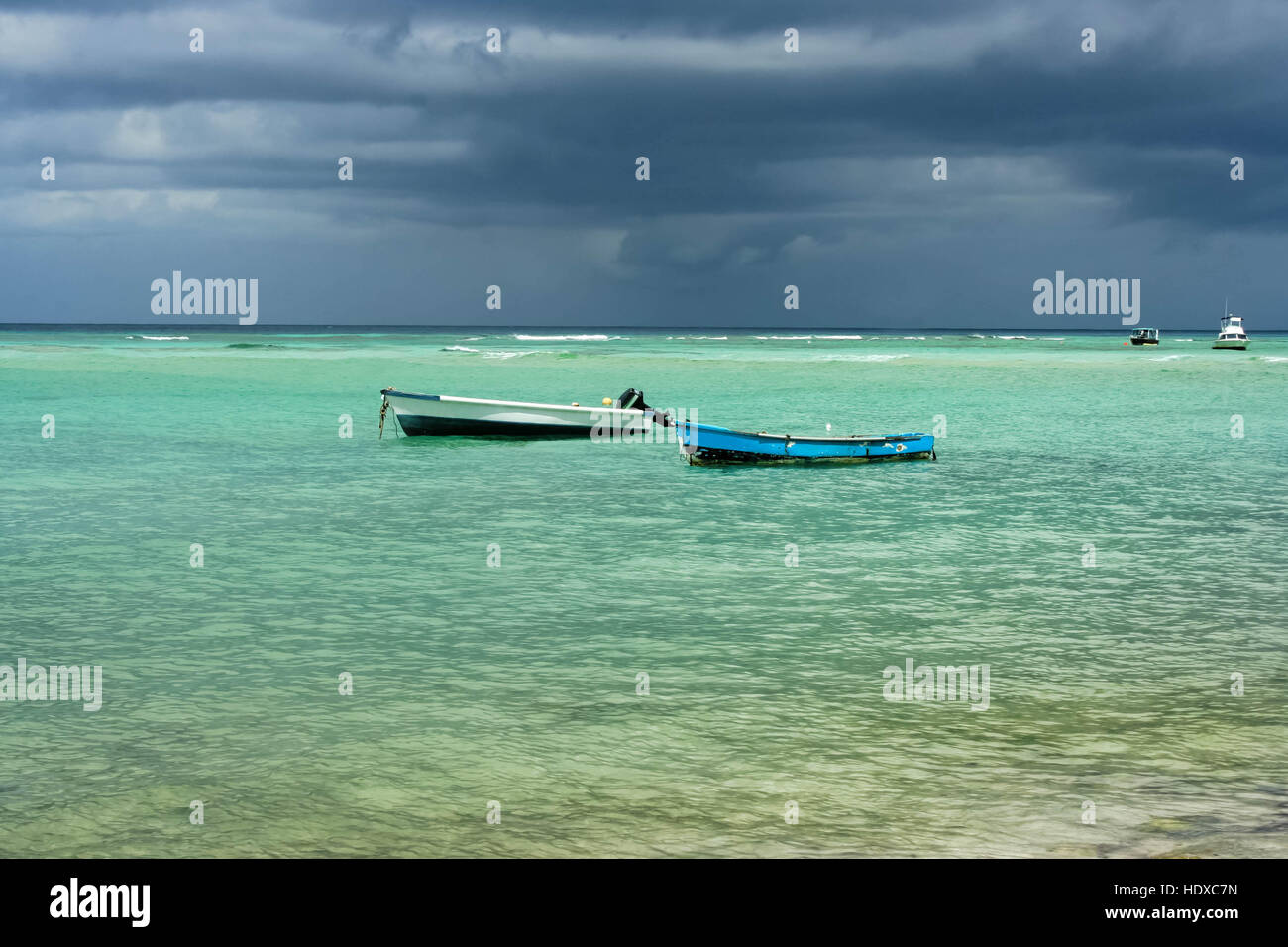 Two old fishing boats in clear sea with a storm background Stock Photo