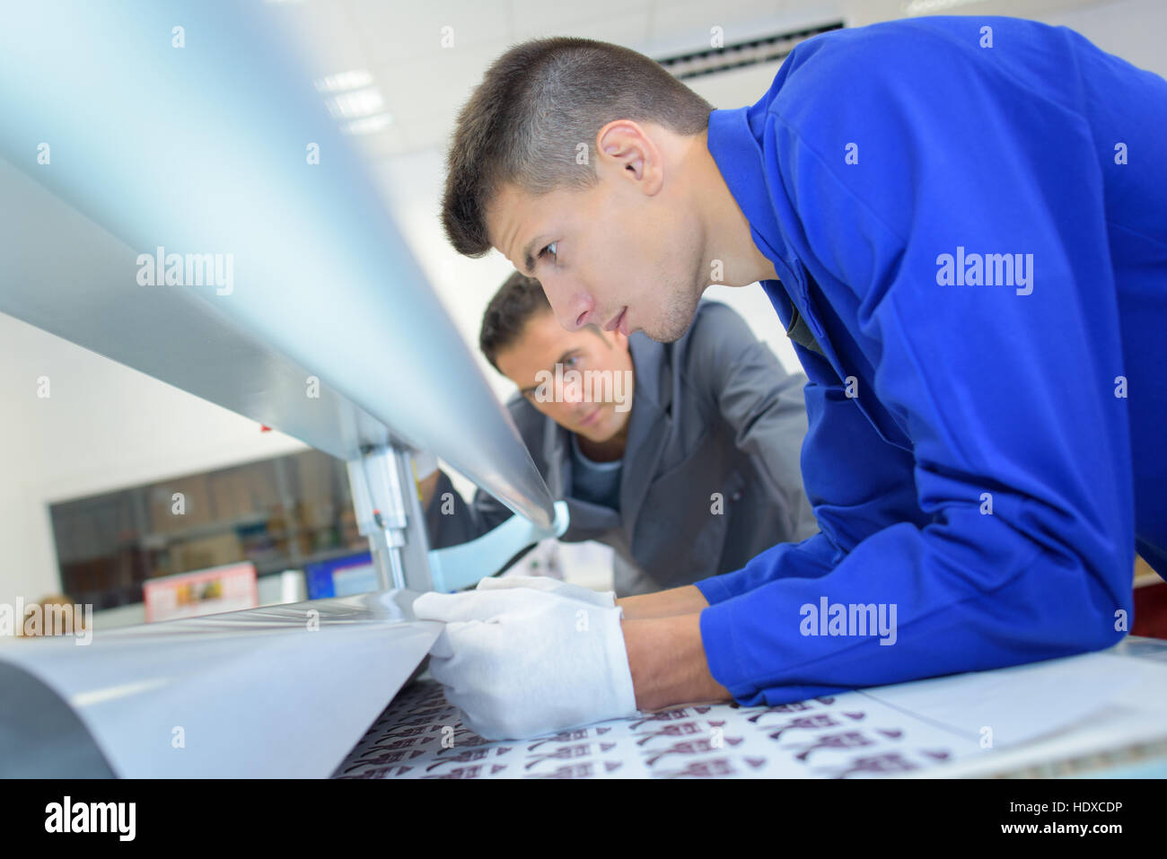 Man pulling paper through printing machine Stock Photo Alamy