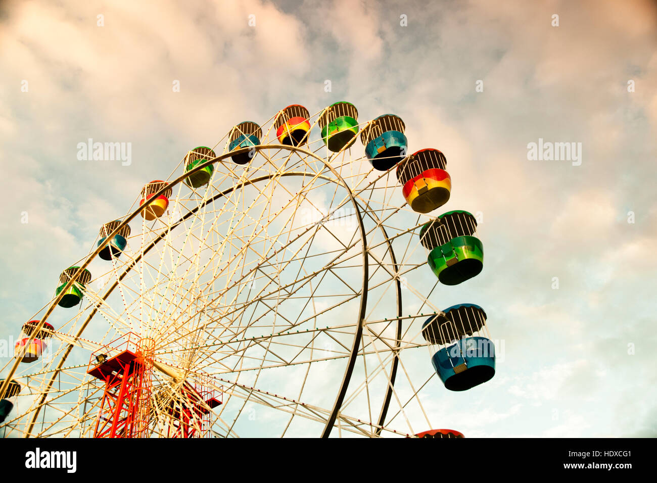 Colorful ferris wheel in sunset with cloudy sky Stock Photo