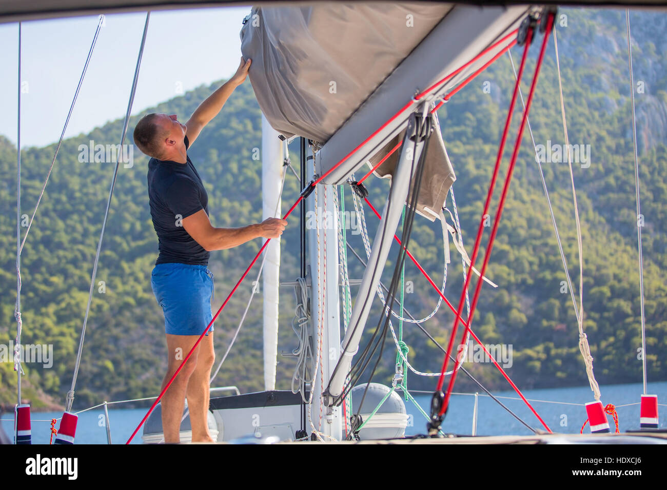 Yachtsman pulls the rope controlling the sail on sailing boat Stock ...