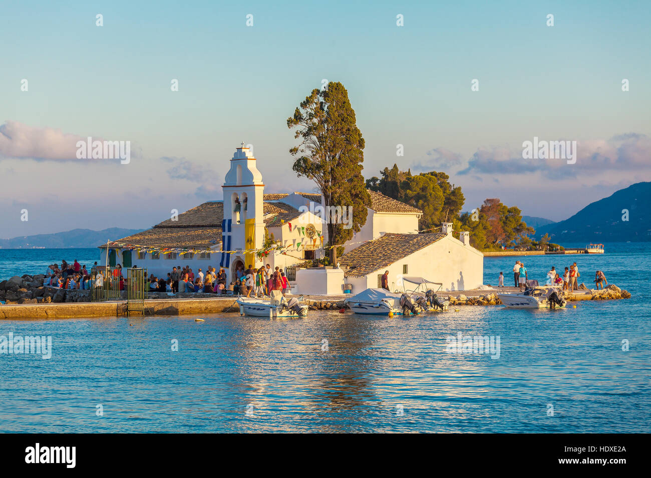 CORFU, GREECE - JULY 2, 2011: Tourists walking in front of Vlacherna monastery at sunset, decorated in honor of the patronal feast Stock Photo