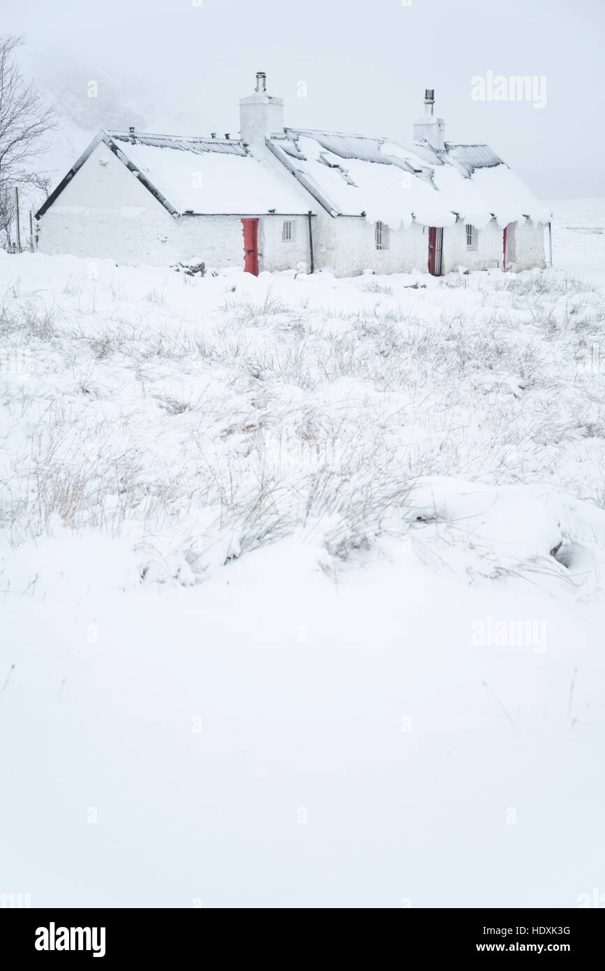 Snow covered traditional cottage covered in snow in the winter in the scottish highlands Stock Photo