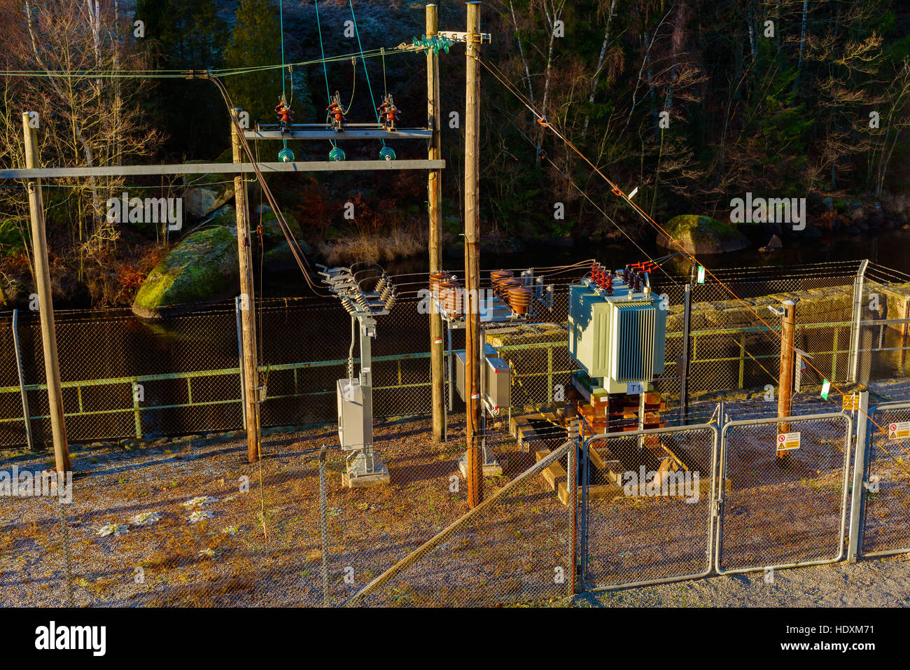 Brantafors, Sweden - December 14, 2016: Documentary of local power grid. Small power substation with a river in the background. Barbed wire fencing su Stock Photo