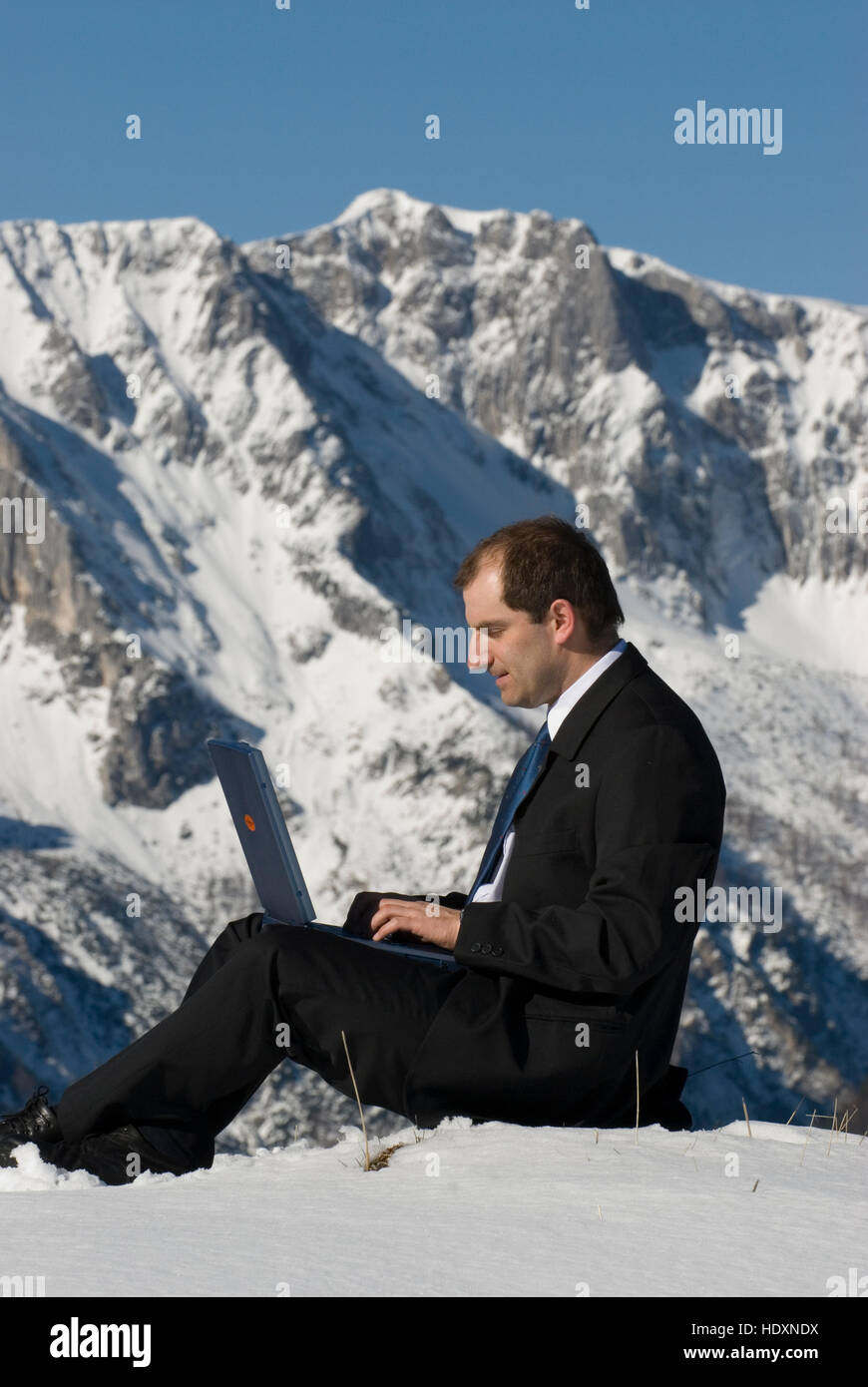 Manager on mountain peak, with a laptop Stock Photo