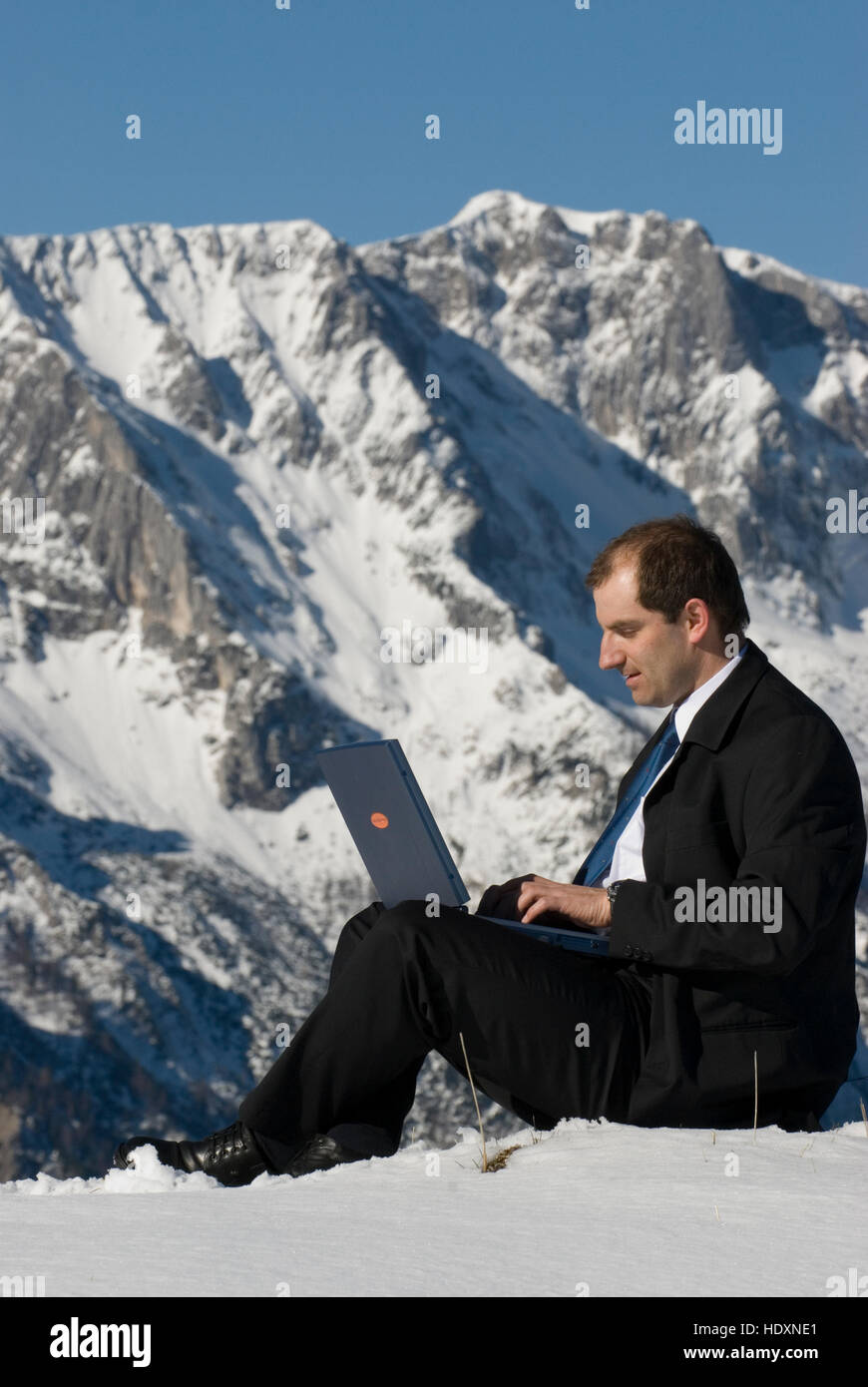 Manager on mountain peak, with a laptop Stock Photo