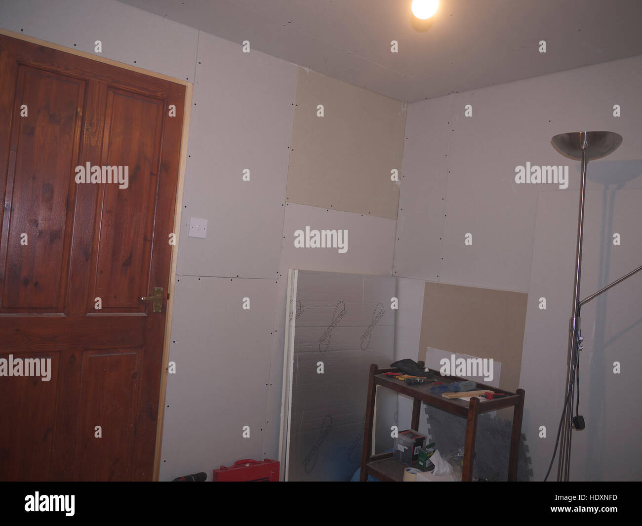 Stud wall in the process of being plasterboarded and insulated Stock Photo