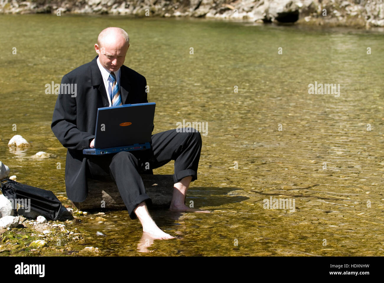 Businessman working while sitting in a mountain brook Stock Photo