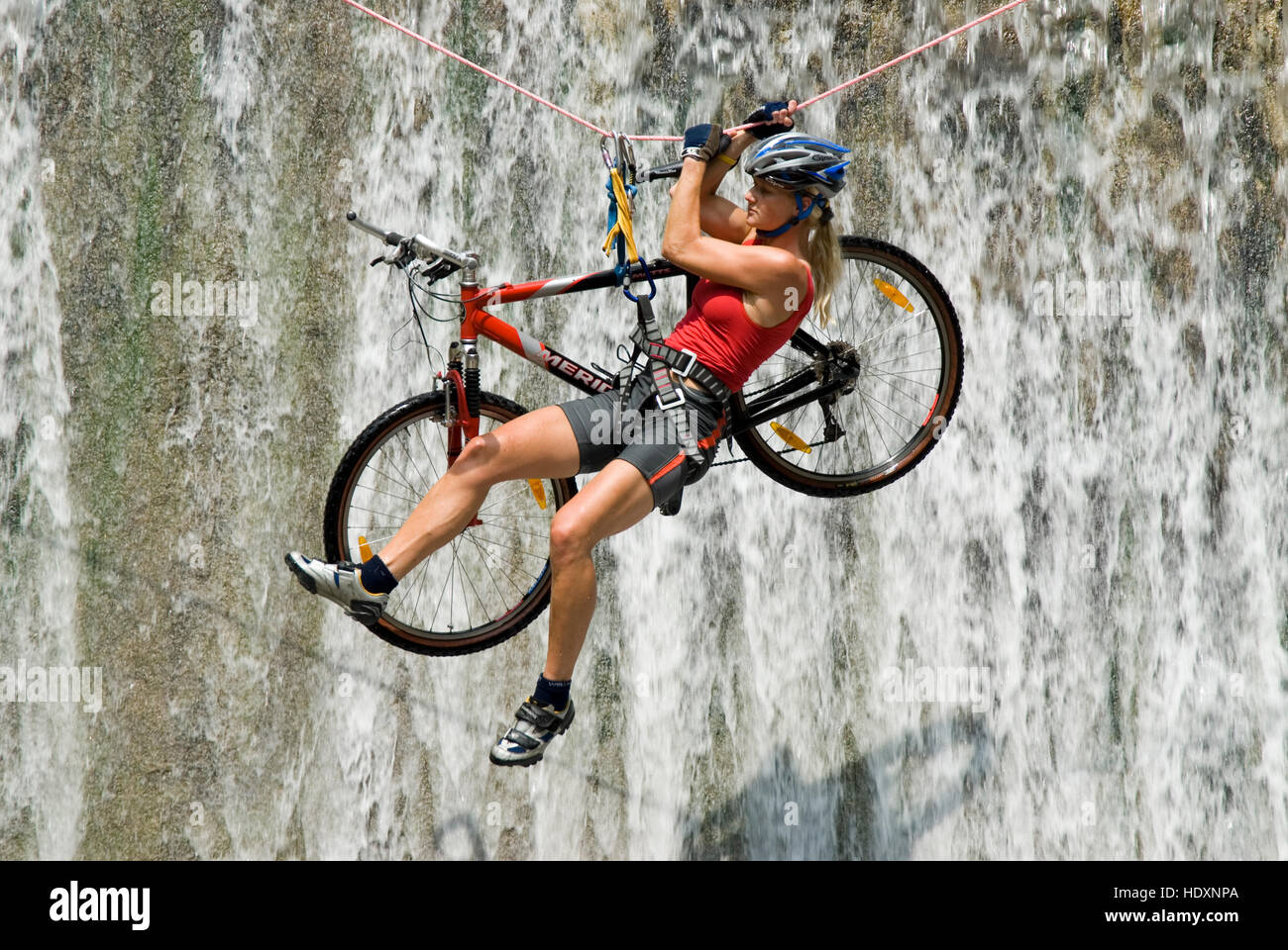 Woman crossing a waterfall on a rope with a bike, Kalkalpen National Park, Upper Austria, Austria, Europe Stock Photo